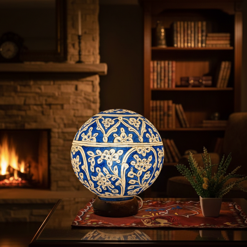 Decorative blue and white spherical lamp on a table with a fireplace and bookshelf in the background